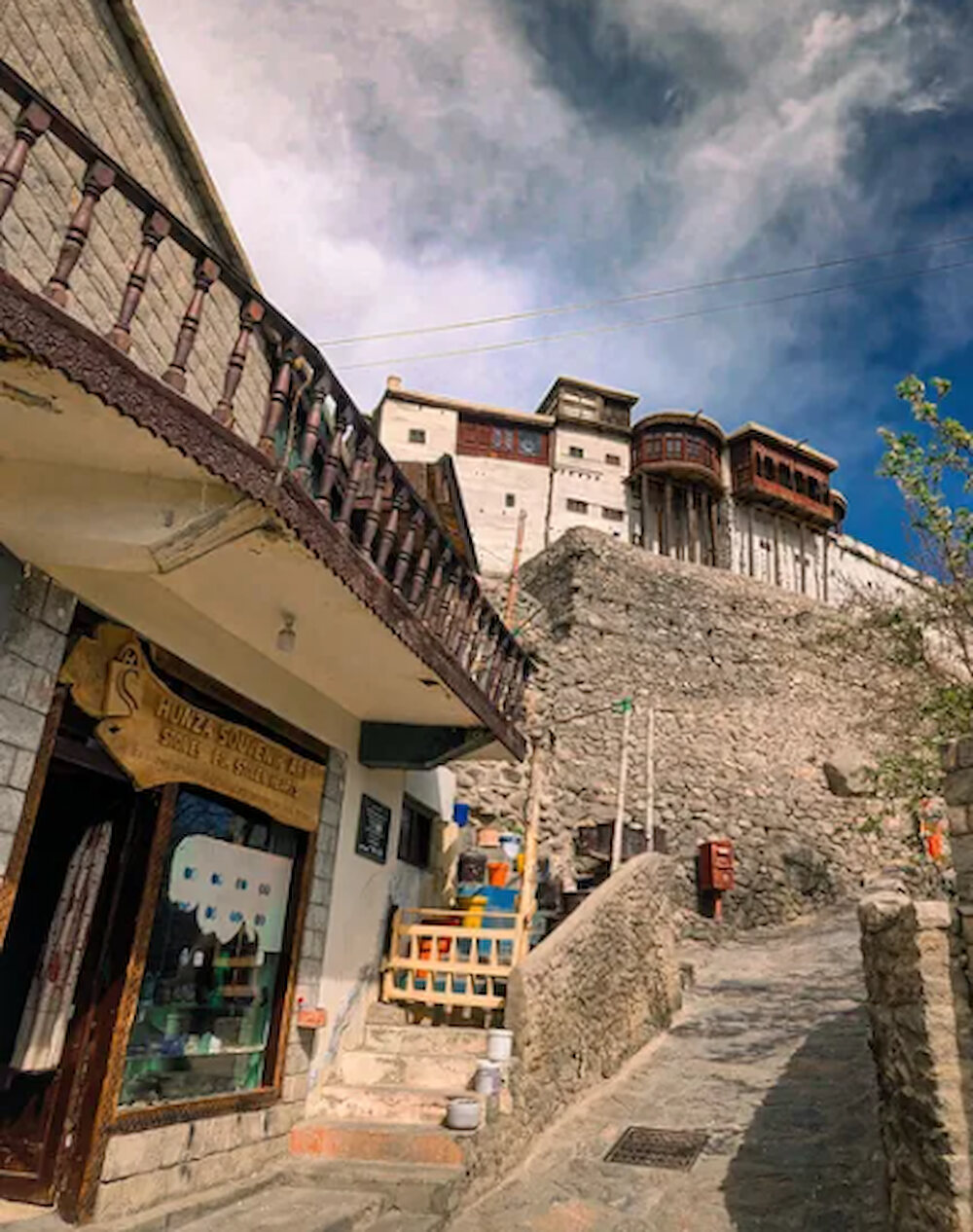 A shopfront and stone stairway below Baltit fort in Karimabad, Hunza